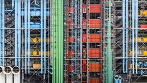 Façade avant du Centre Pompidou à Paris, avec son architecture industrielle haute en couleurs. Les tuyaux bleus, verts, rouges et jaunes ressortent sur la structure métallique apparente. Cette vision urbaine, dynamique et futuriste symbolise l'audace architecturale du bâtiment conçu par Renzo Piano et Richard Rogers.